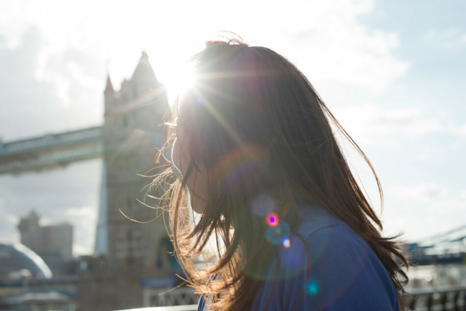 A woman is standing in front of Tower Bridge during her travel diary in London.