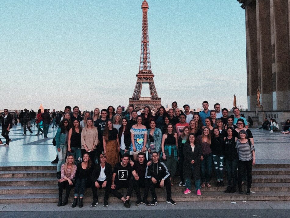 A group of people posing in front of the Eiffel Tower.