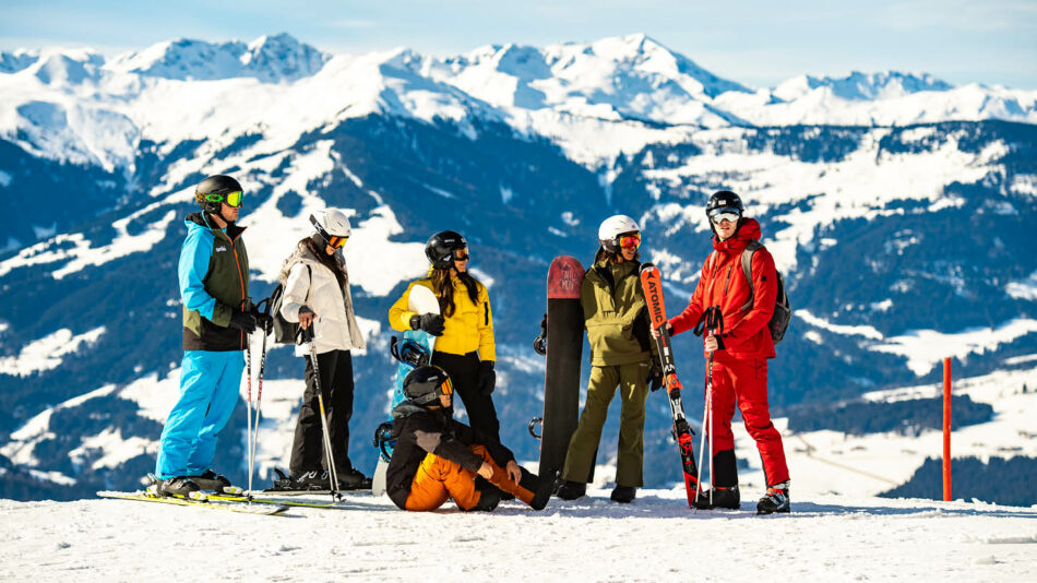 A group of people on a ski trip standing on top of a mountain.