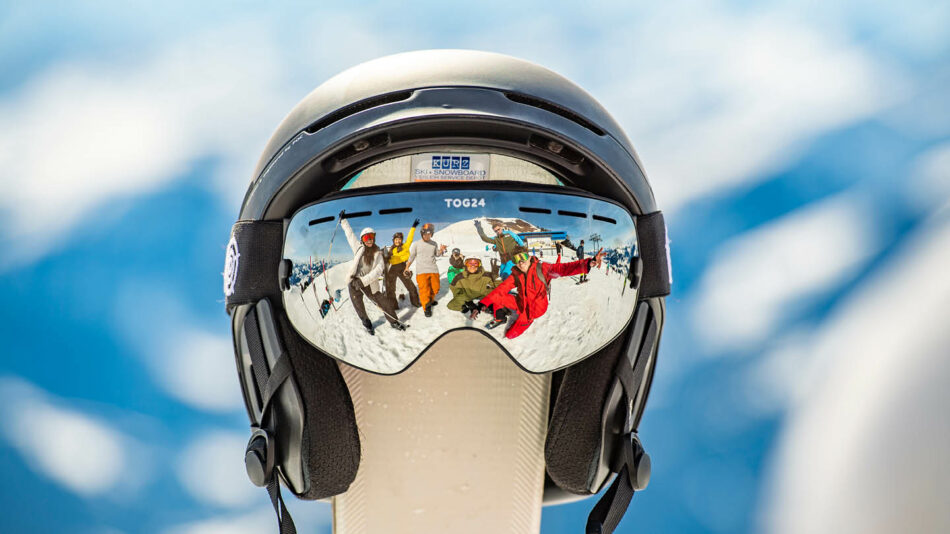 A group of ski enthusiasts wearing ski goggles on top of a mountain during their trip.