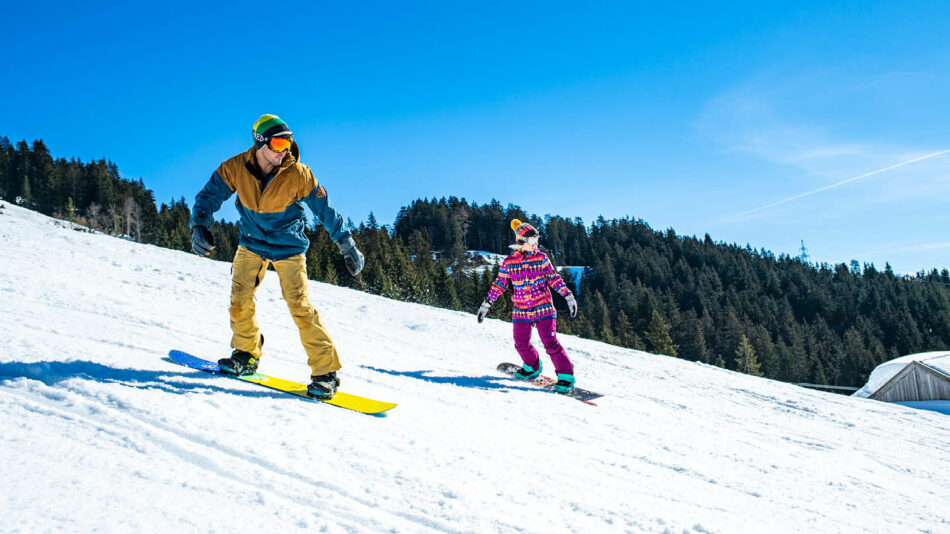 A man and a child enjoying a thrilling snowboarding experience.