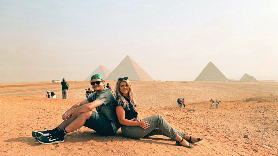 Friends sitting in front of Pyramids of Giza in Egypt