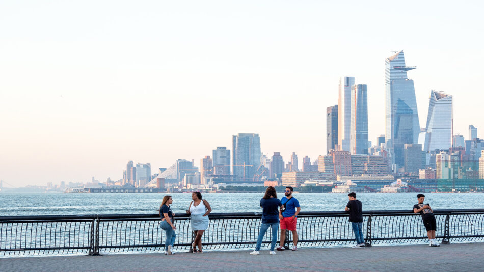 A group of people standing on a railing near the water.