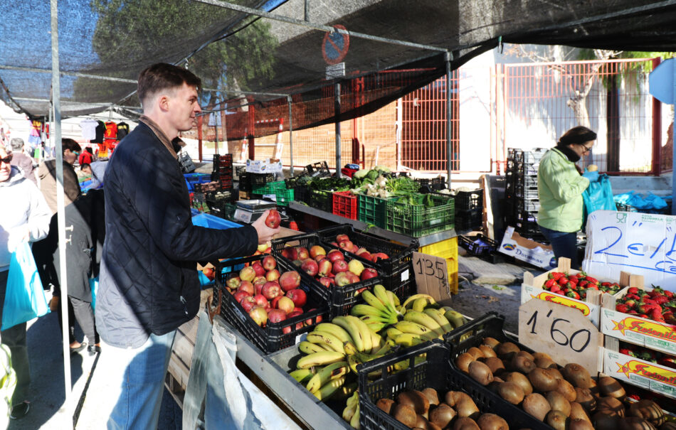 A budget-conscious traveler buying fruit at an outdoor market during backpacking.