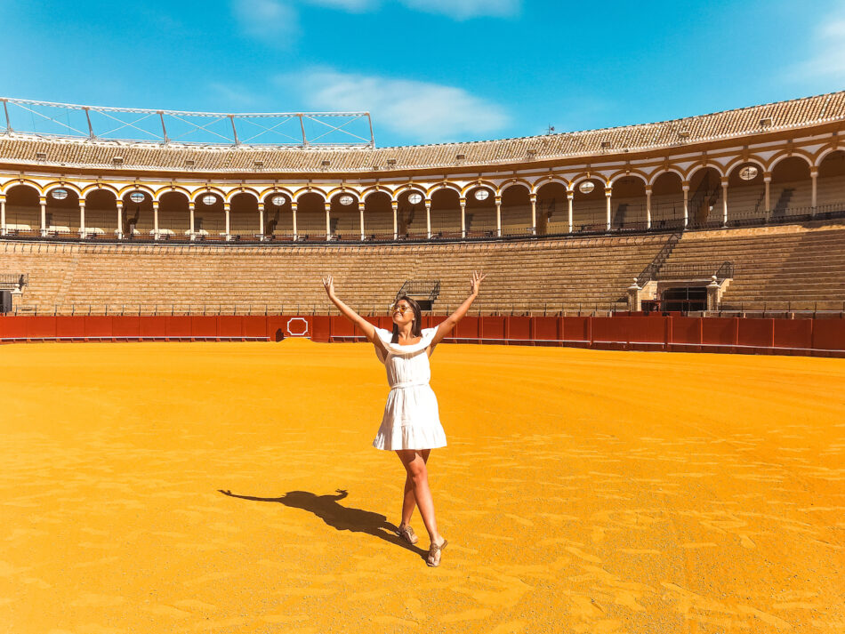 A woman in a white dress gracefully standing in an arena, capturing enchanting travel photos.