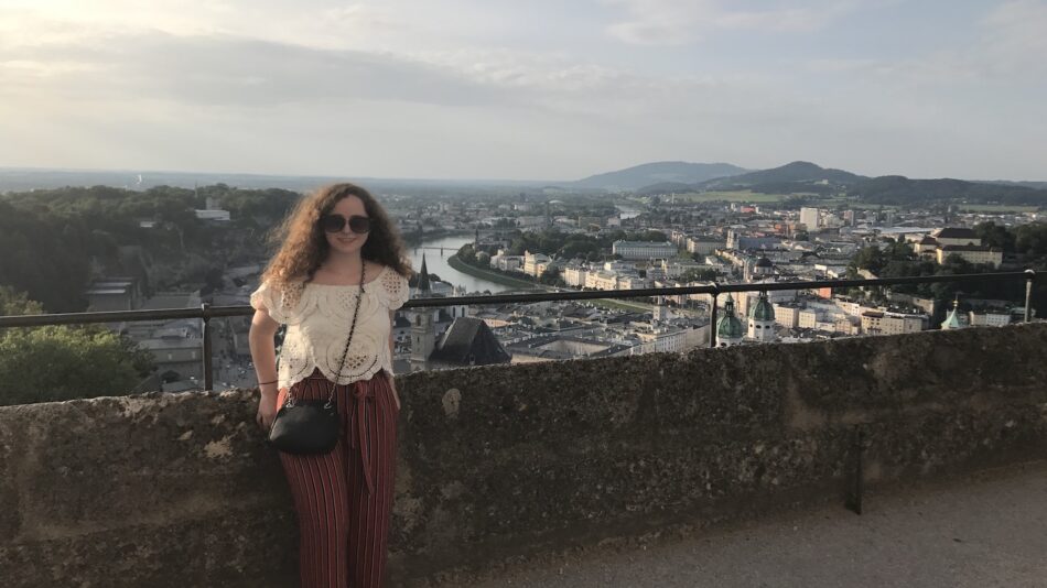 A woman standing on top of a wall overlooking a city.