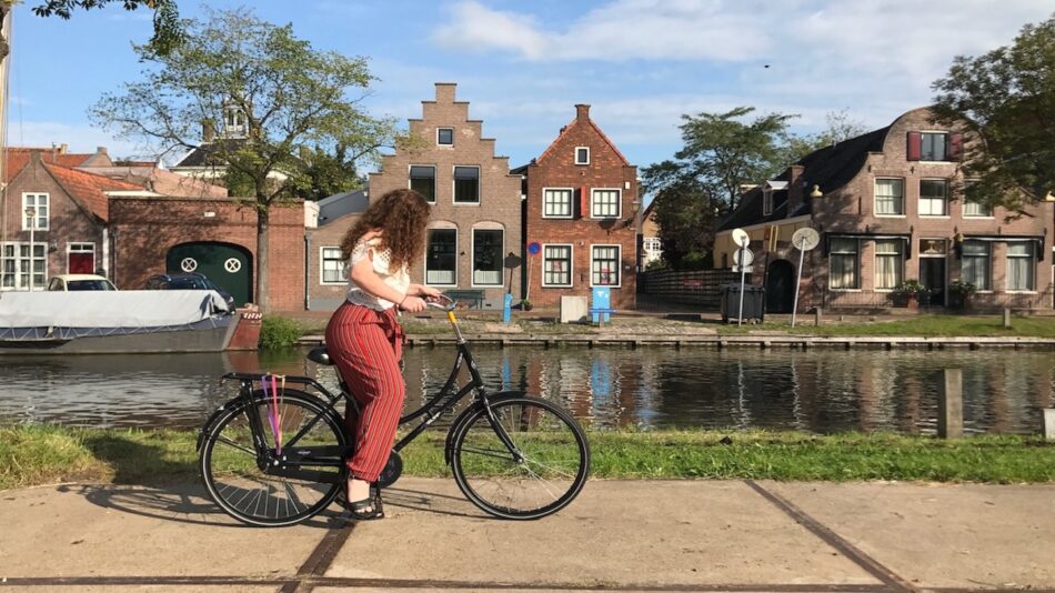 A woman riding a bike in front of a canal.