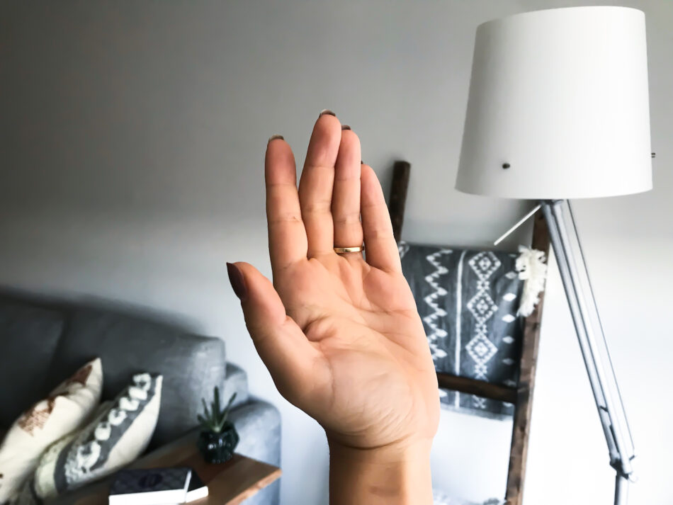 A woman demonstrates how to create better travel photos by holding up her hand in front of a lamp, creating a unique and captivating light effect.