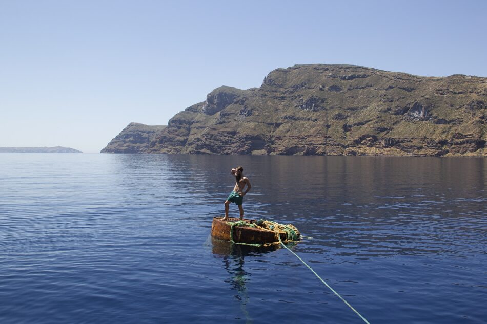 A man standing on a boat in the water during his 72 hours in Greece.