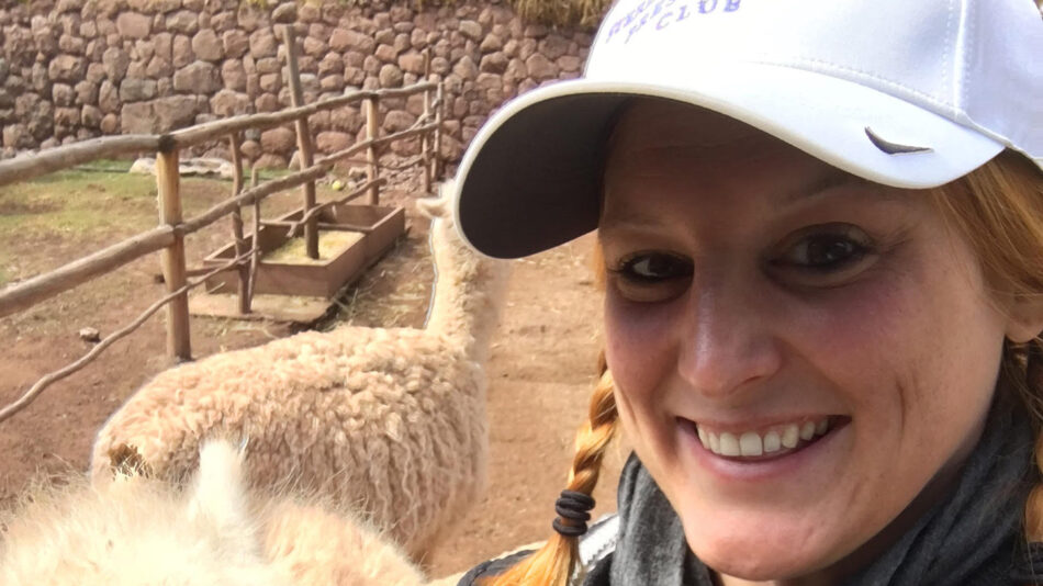 A woman smiles while holding an alpaca on the Inca Trail tour.