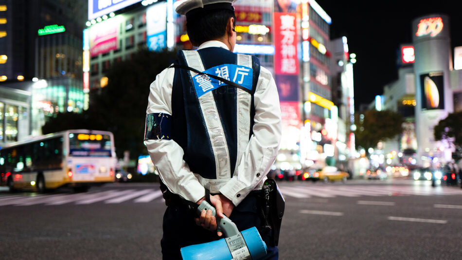 A japanese police officer standing on a city street at night.