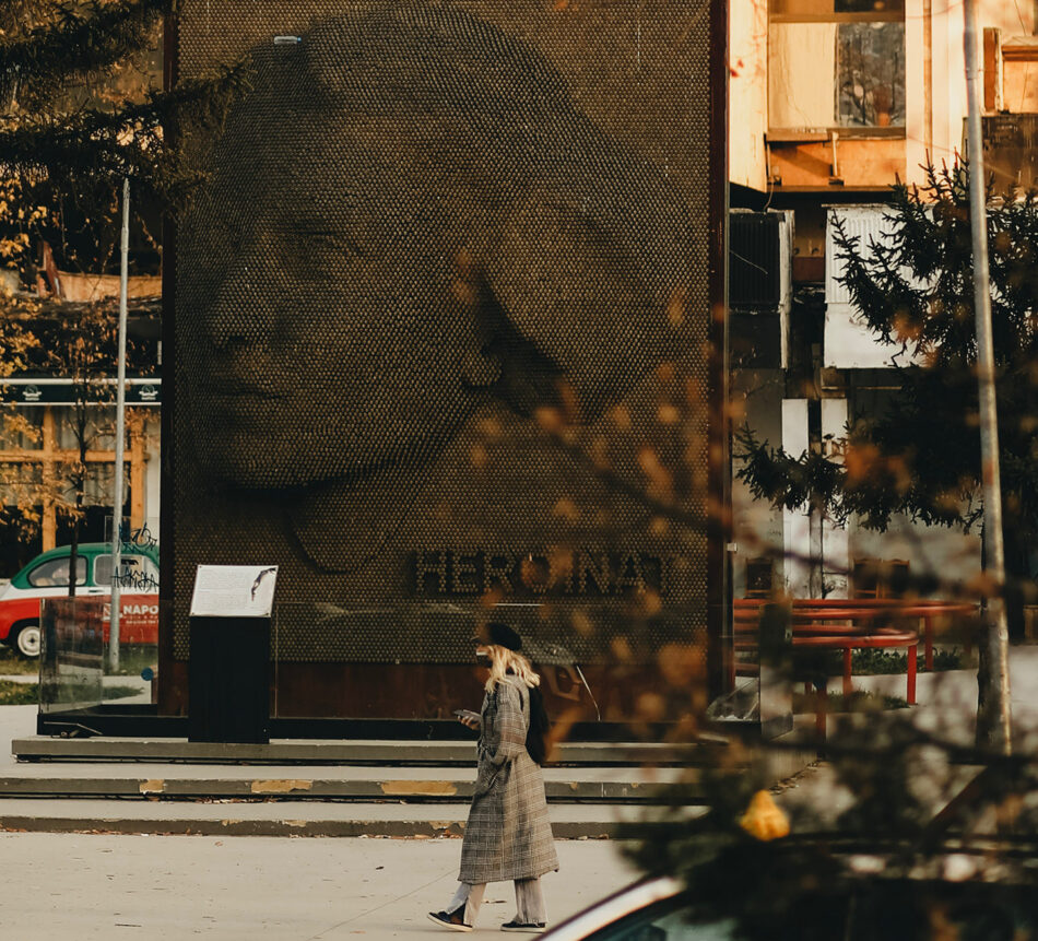 A woman walking past a statue of a woman.