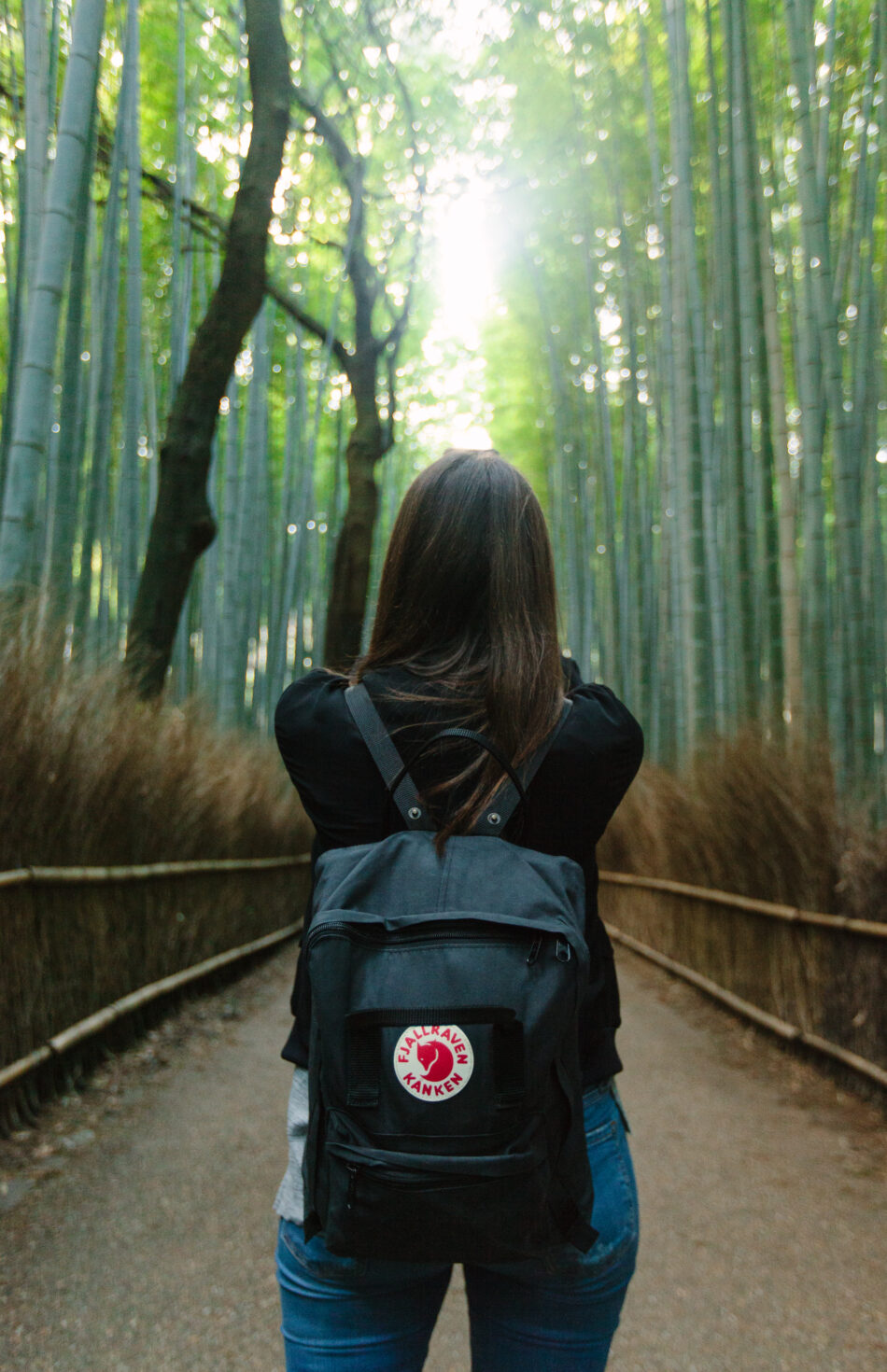 A tourist with trendy backpack looking up through a forest