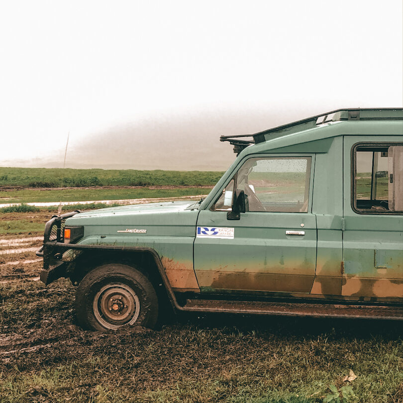 A green toyota land cruiser parked in a muddy field.