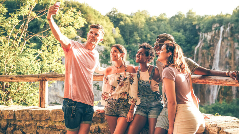 A group of friends taking a selfie in front of a waterfall.