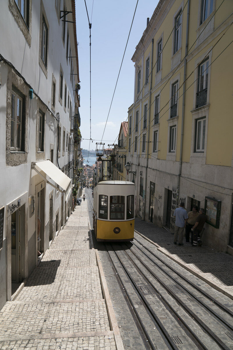 A trolley car is going down a cobblestone street during a trip to Portugal.