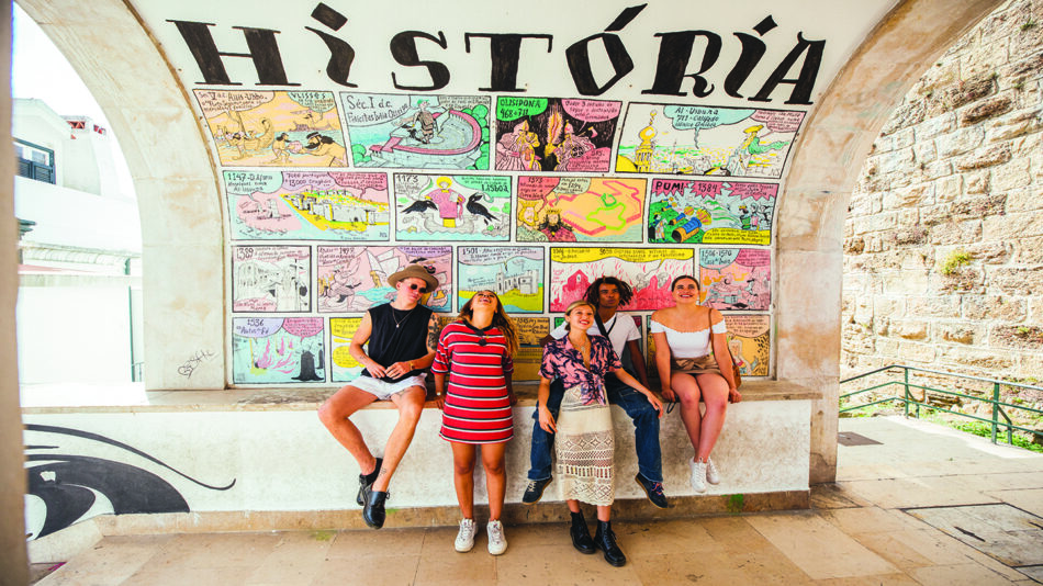 A group of people capturing local experiences in front of a mural.