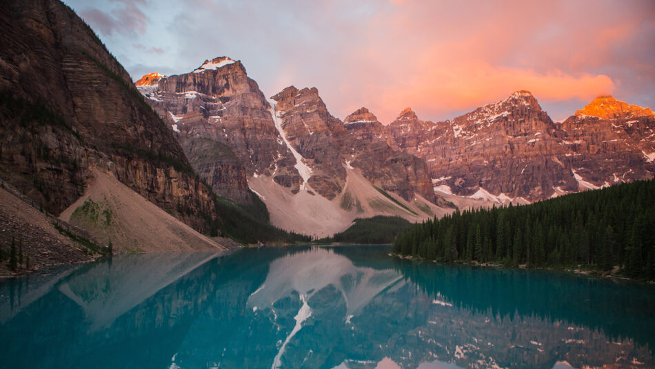 The mountains are reflected in a lake at sunset.