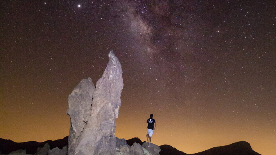 A man standing on a rock looking up at the milky.