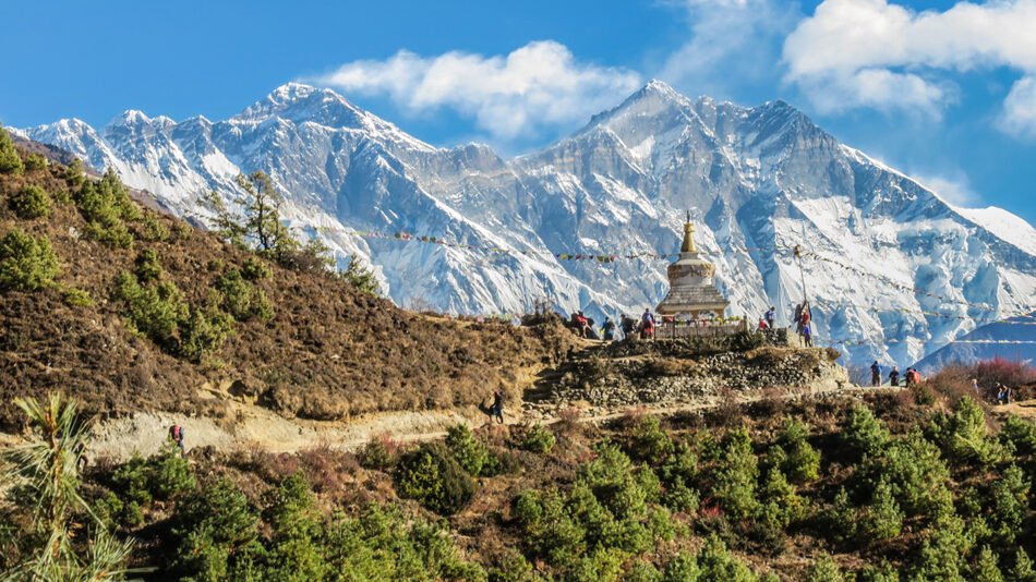 A group of people standing on top of a mountain in nepal.