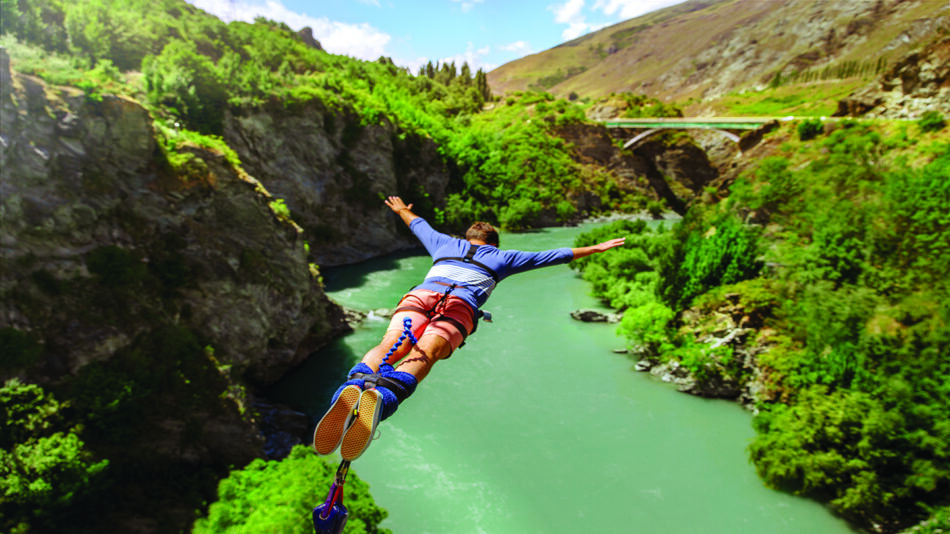 A person is hanging from a rope over a river.