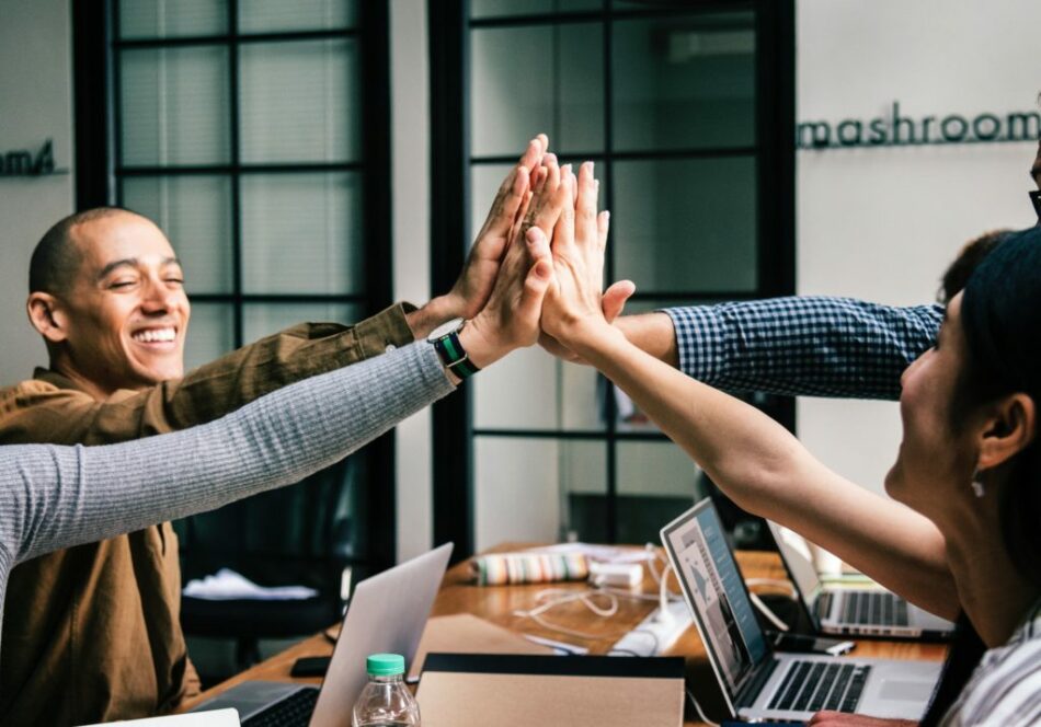 A group of people giving each other high fives in a remote work meeting.