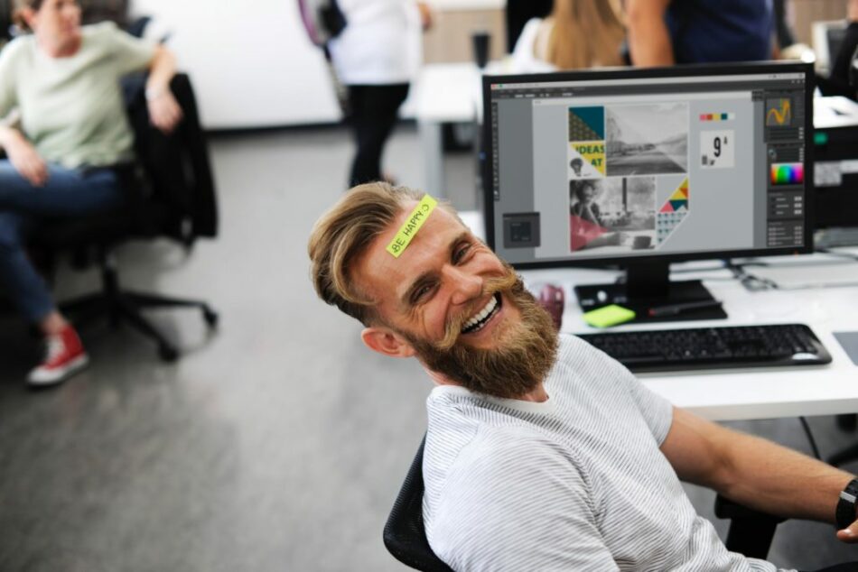 A man with a beard sitting in front of a computer.