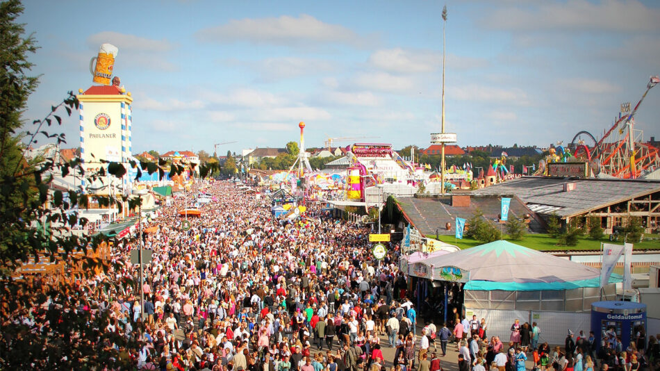 A crowd of people at an amusement park during Oktoberfest.