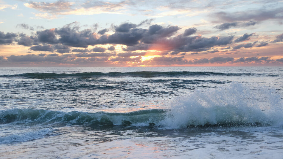 Experience the mesmerizing sight of waves crashing on the beach at sunset, one of the best places to visit in August.