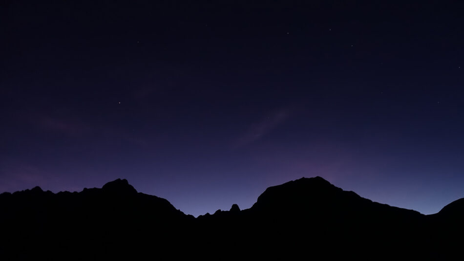 A silhouette of a mountain range at night.