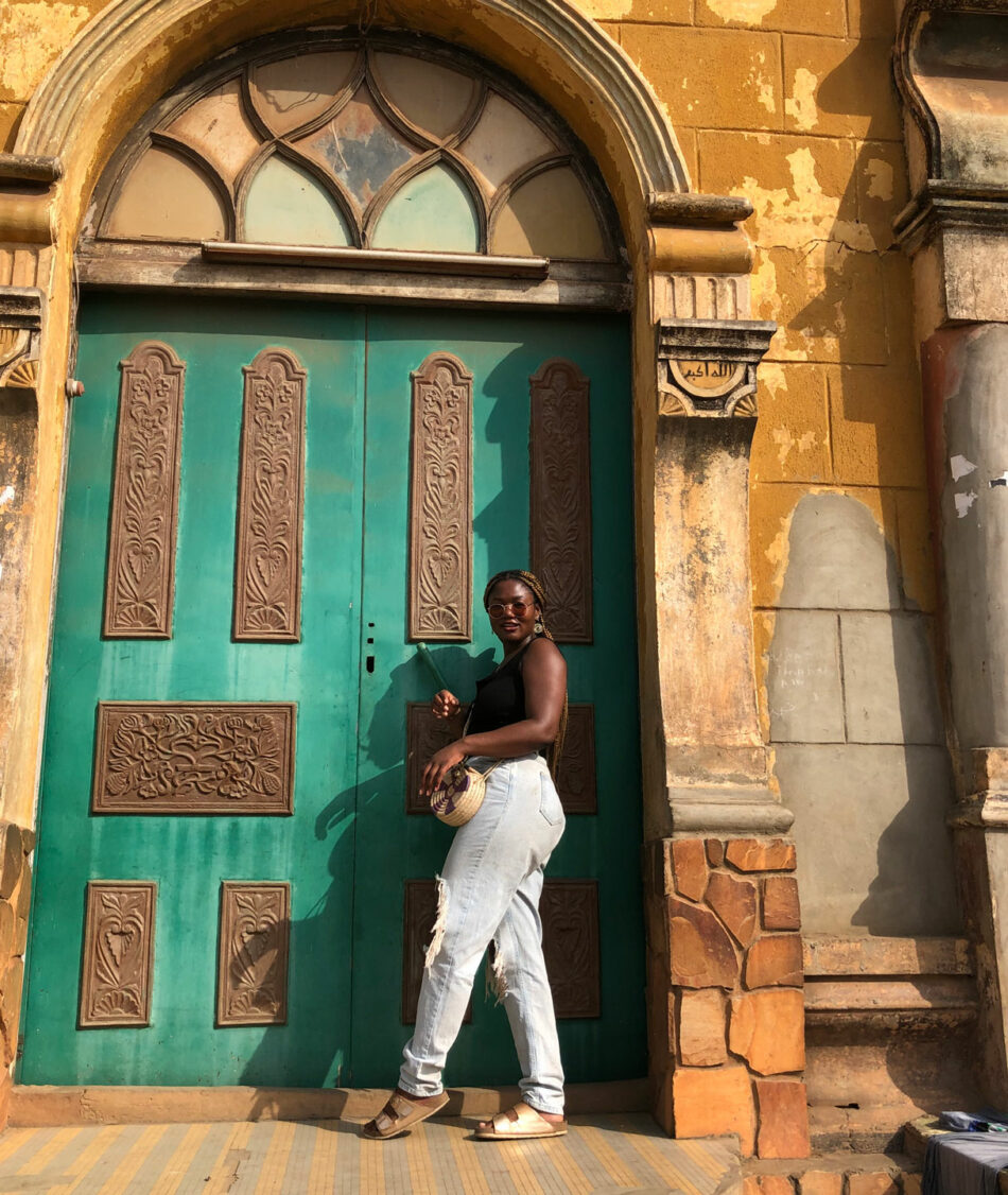 A woman standing in front of a green door.