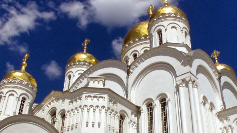 A white church with golden domes against a blue sky.