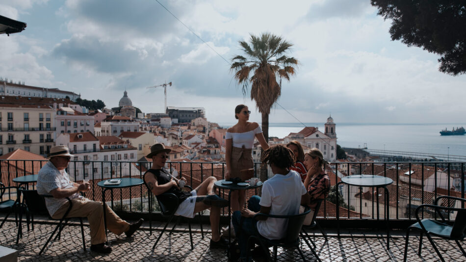 A group of people sitting on a balcony overlooking the city of lisbon.