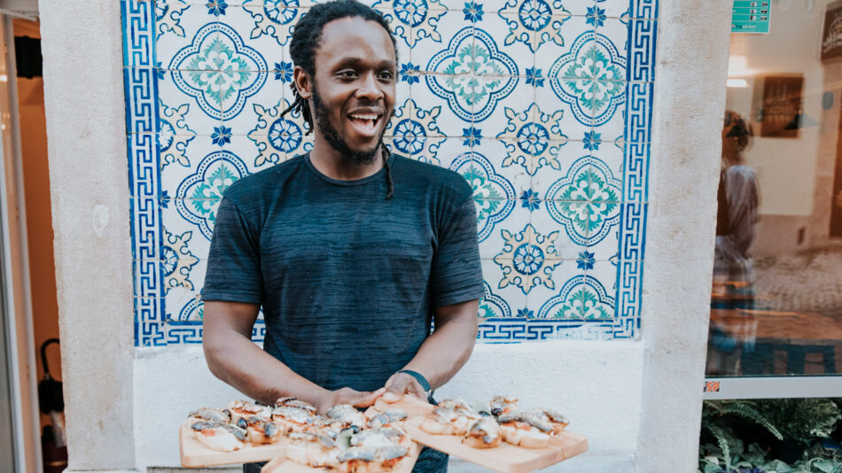 A man holding a tray of food in front of a tiled wall.