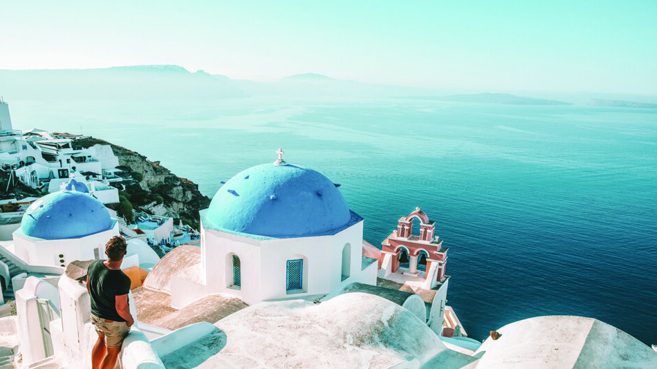 Amidst the captivating scenery, a man eagerly embraces the breathtaking view of the ocean from a cliff.