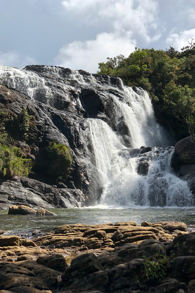 A scenic waterfall nestled among majestic rocks and lush trees, highlighting top 2019 destinations.