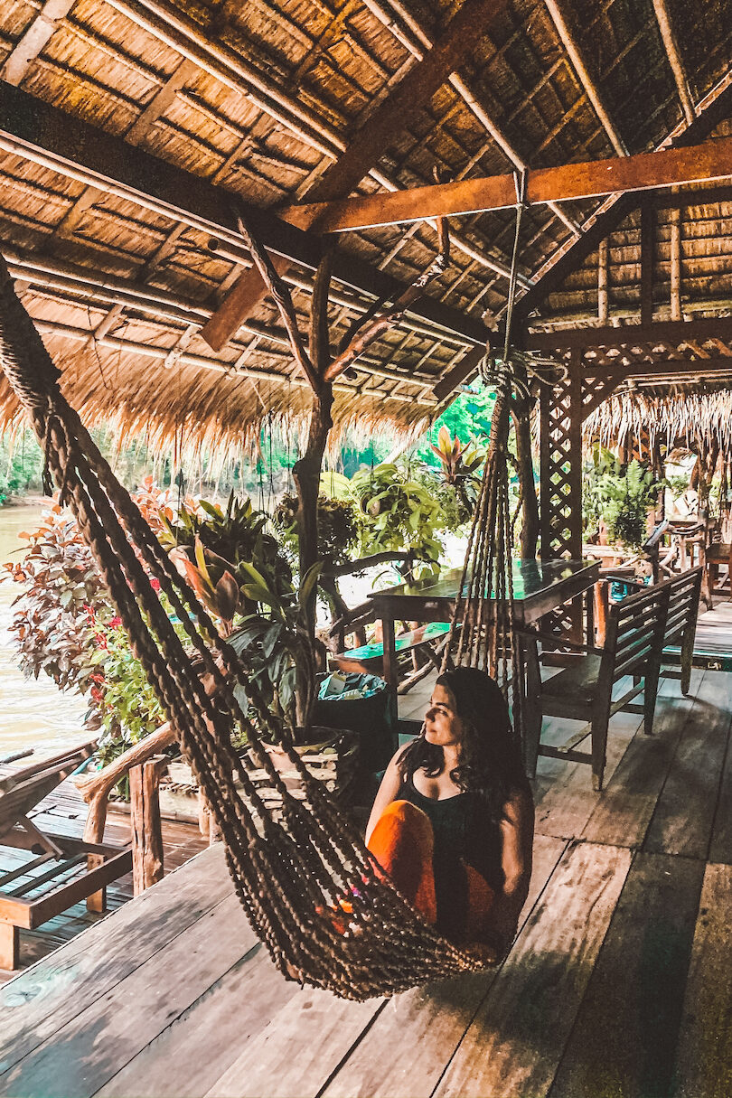 A woman sitting in a hammock on a wooden deck.