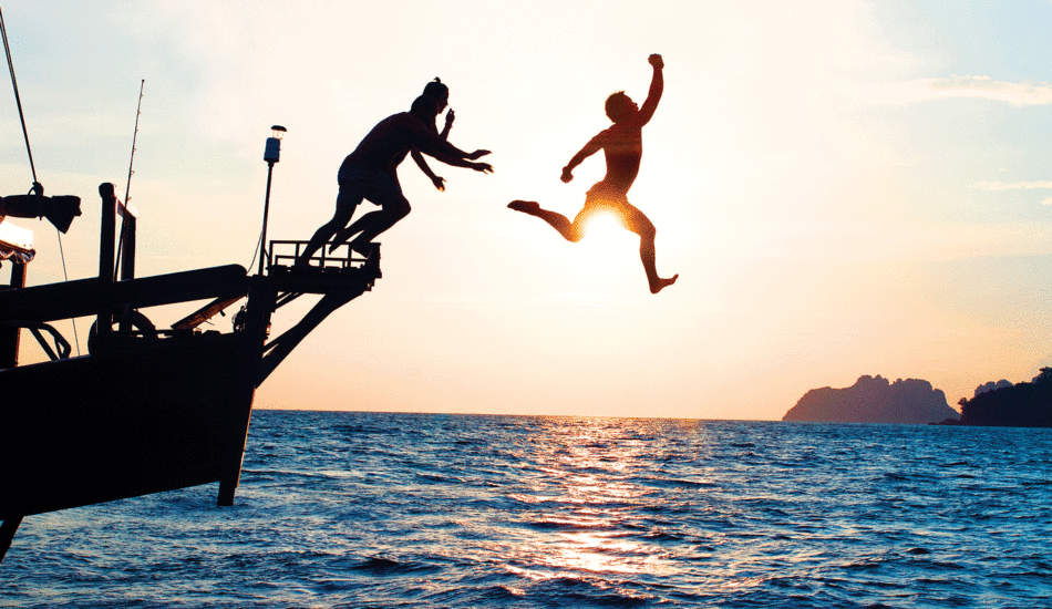 Two digital nomads jumping off a boat in Thailand.