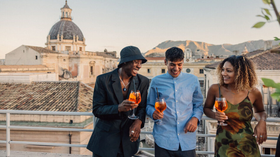 A group of people enjoying a 30th birthday trip on a rooftop with drinks.