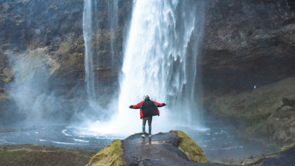 A person standing in front of a waterfall.