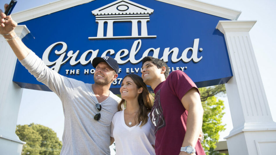 Three people taking a picture in front of the Graceland sign, representing Tennessee's music history.