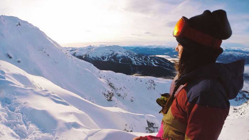 A person is standing on top of a snow covered mountain, one of the breathtaking things to do in North America.