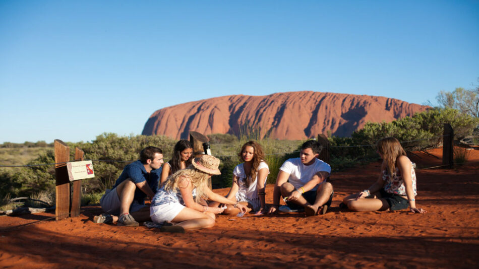 A group of people on an Australia holiday sitting in front of Uluru.