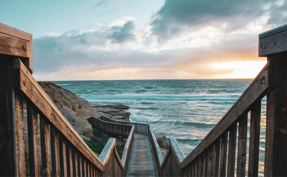 A wooden stairway leading to the ocean.