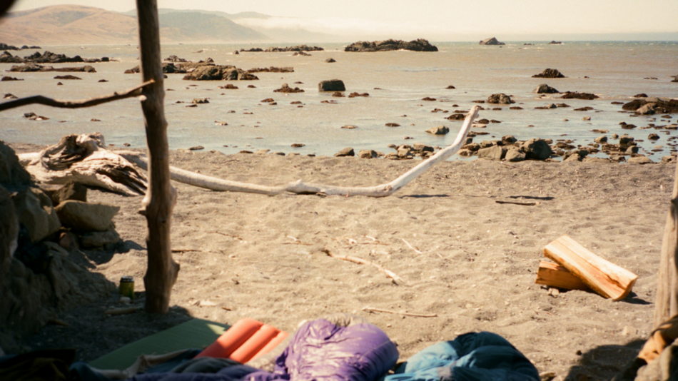 A group of sleeping bags on a beach.