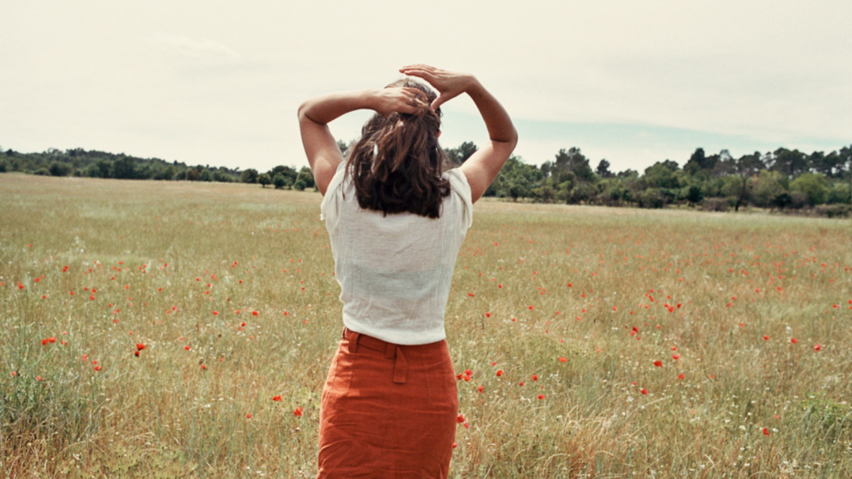 A woman standing in a field of poppies.