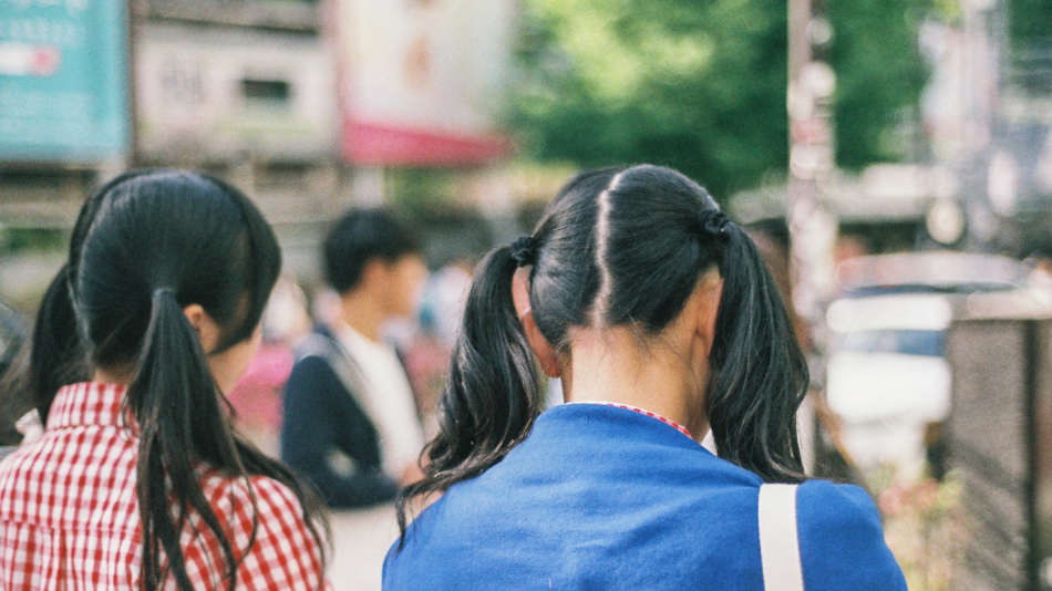 Two asian girls walking down the street.