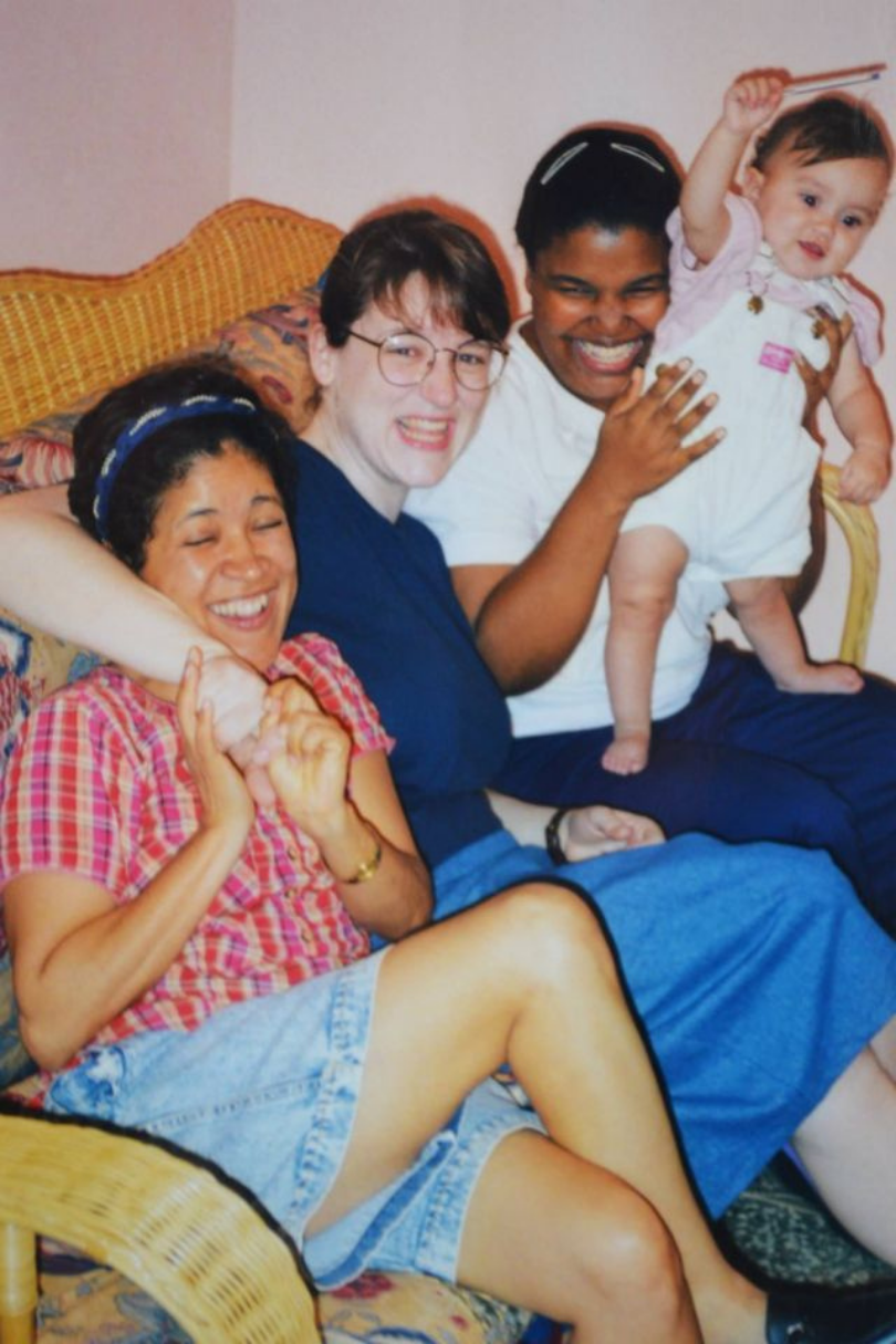 Three women sitting on a couch with a baby.