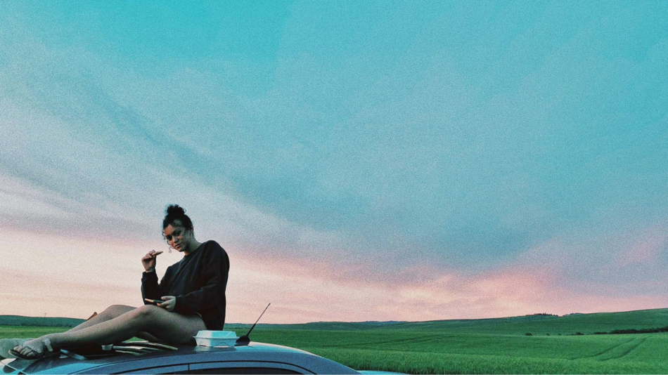 A woman sitting on the hood of a car.