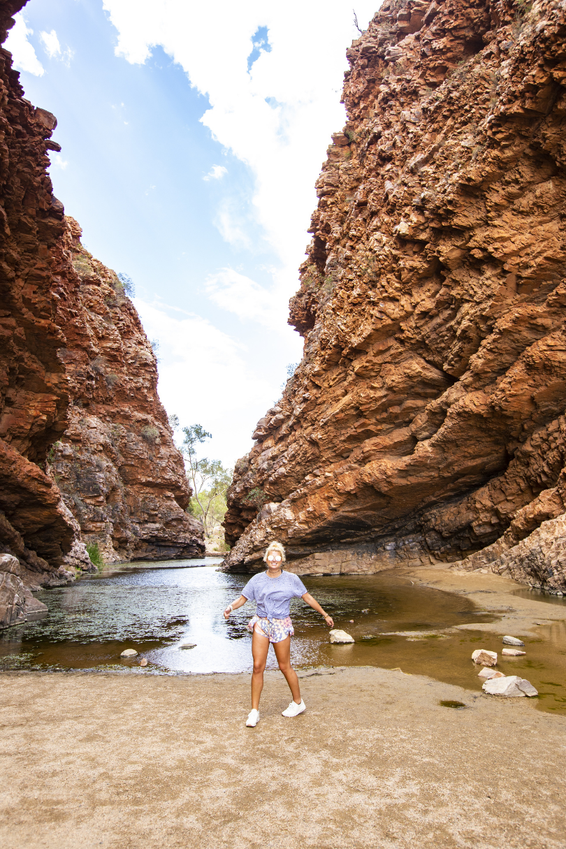 A woman standing in front of a river in a canyon.